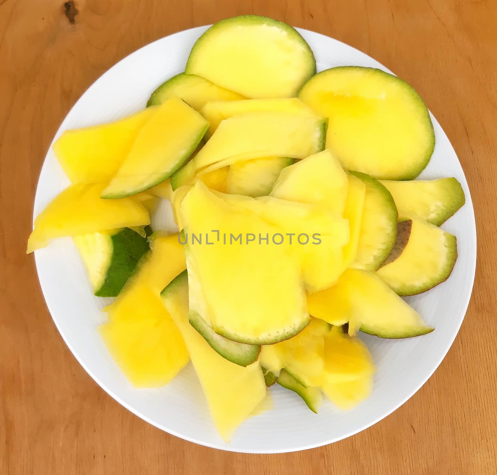 Pineapple sliced in a plate, on a wooden background.