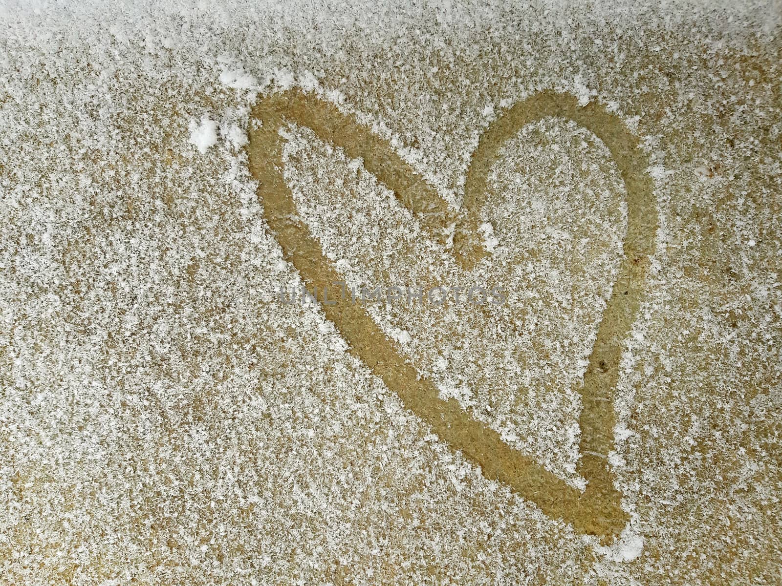 Heart drawn on a thin layer of snow. Valentines day concept.