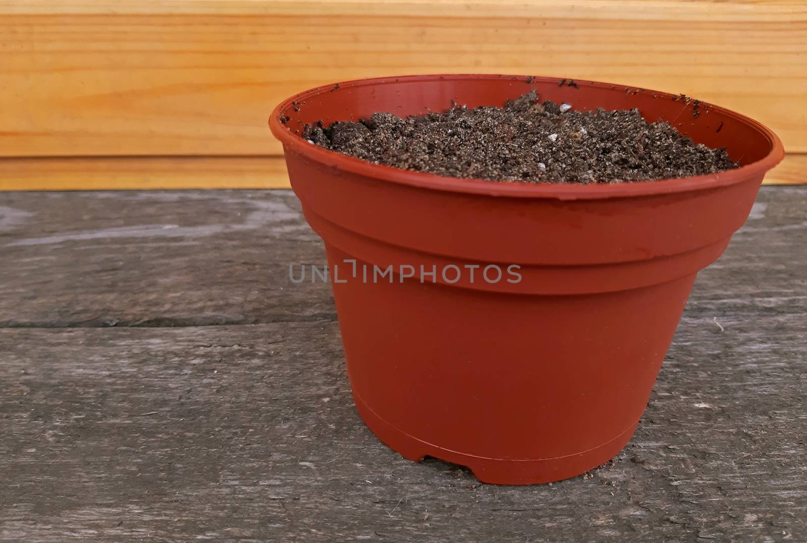 A pot full of potting soil on wooden background.