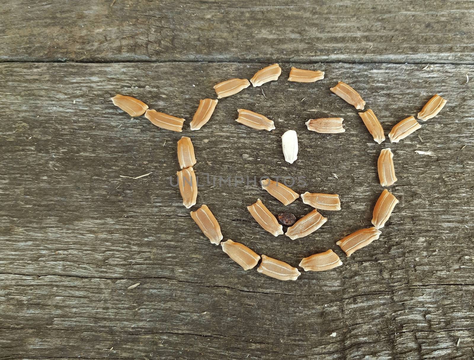 Seeds smiley emoticon shape on wooden bacground.