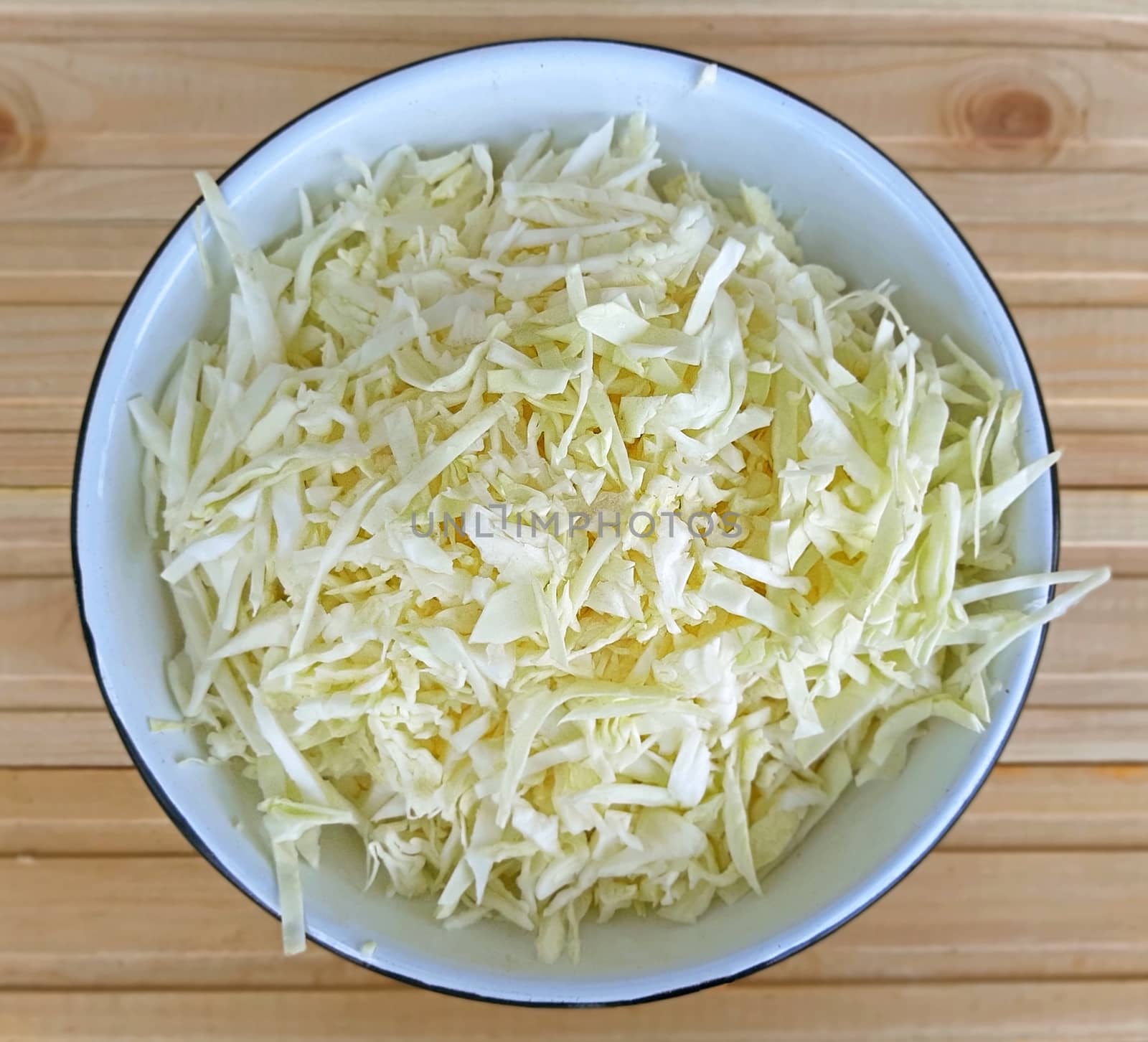 Chopped fresh cabbage in a bowl. Wooden Background.