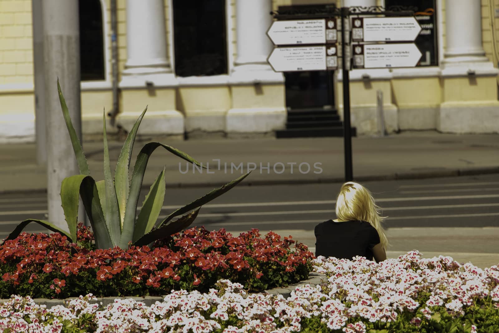 A girl is resting near flowers in the city.