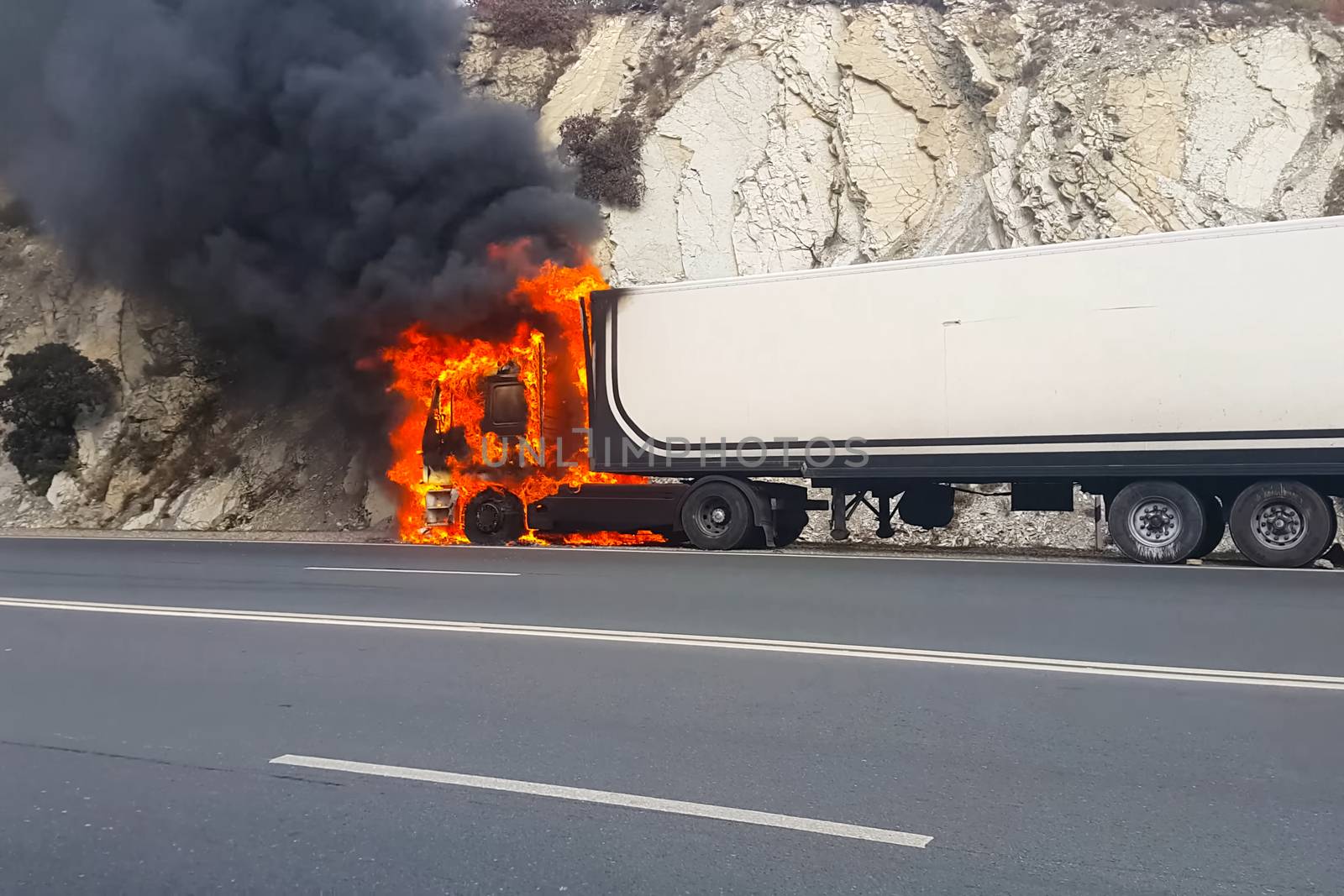 Burning truck on the road. The cab of the truck is on fire.