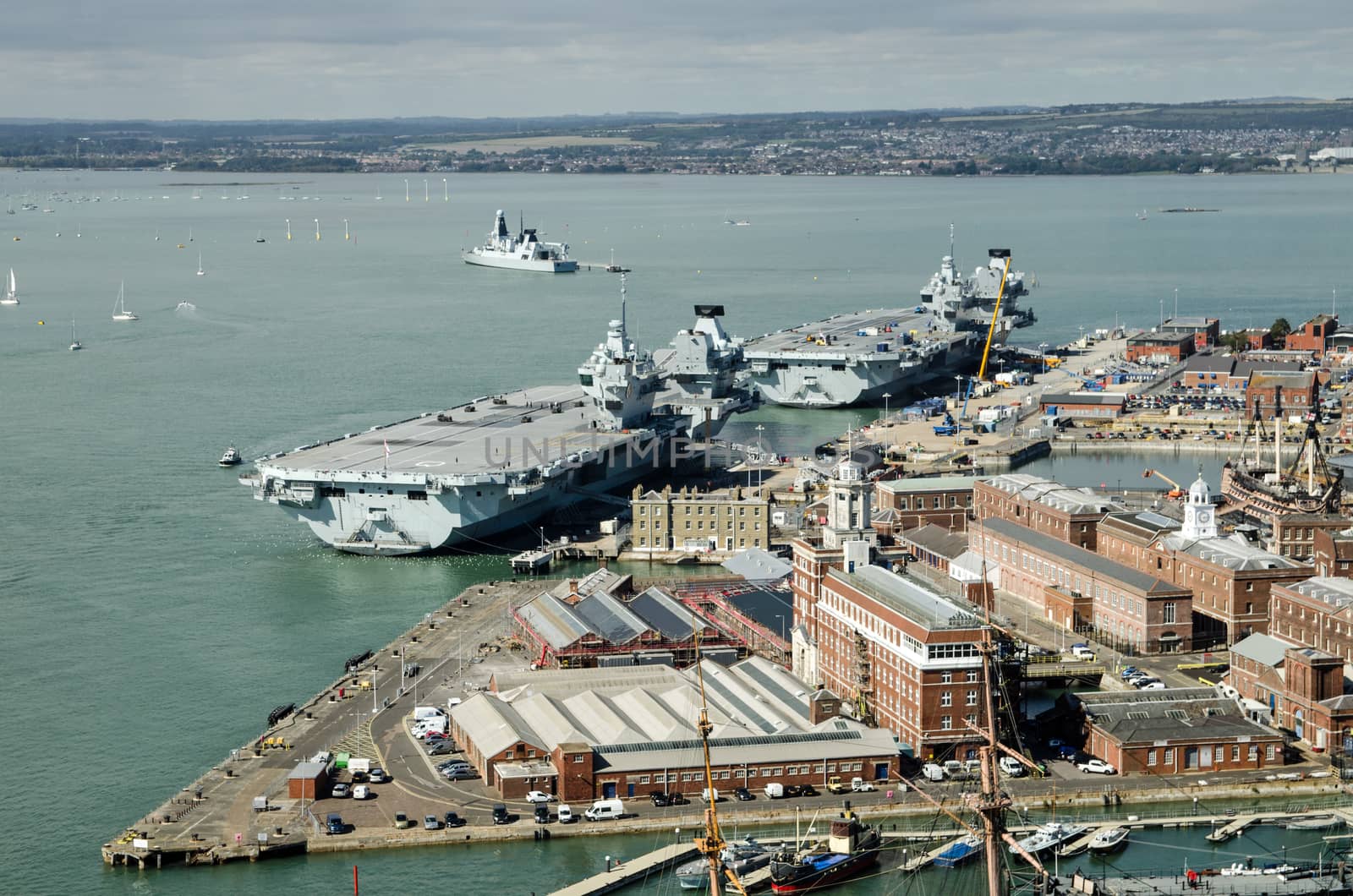 Aerial view of the two largest ships in the Royal Navy, the aircraft carriers Queen Elizabeth and the Prince of Wales moored beside each other in Portsmouth Harbour, Hampshire. To the right of the picture is the Historic Dockyard and the famous Victory which Nelson commanded at the Battle of Trafalgar.