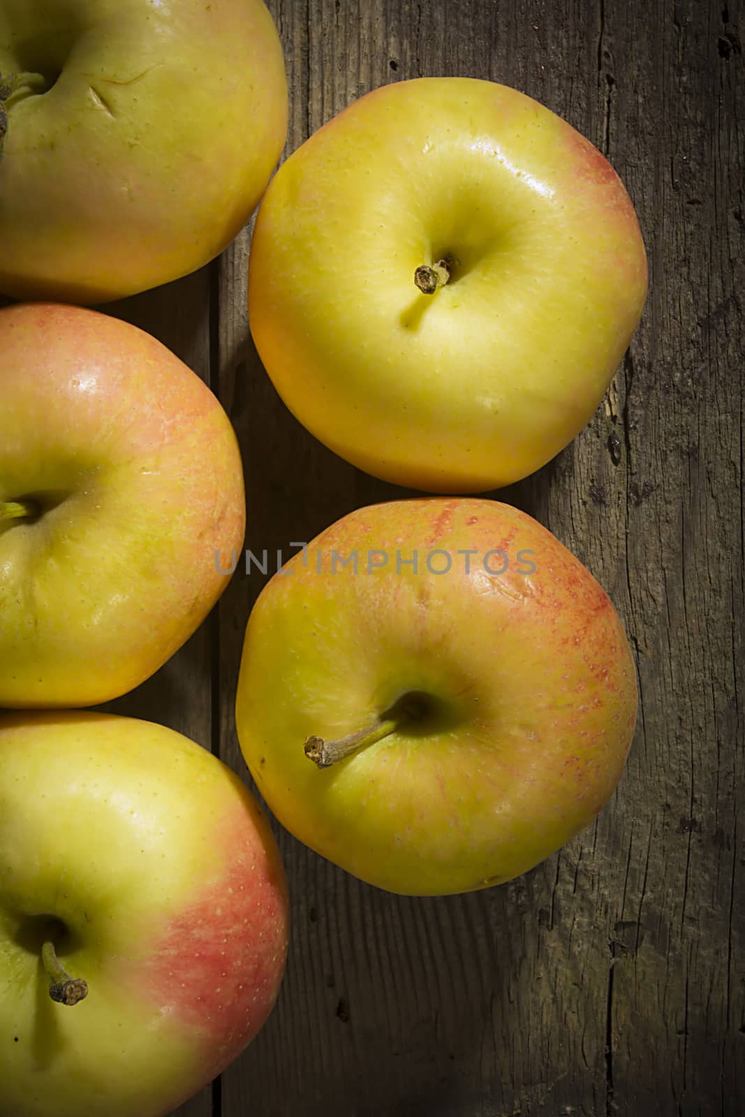 Lots of ripe apples on an old wooden surface