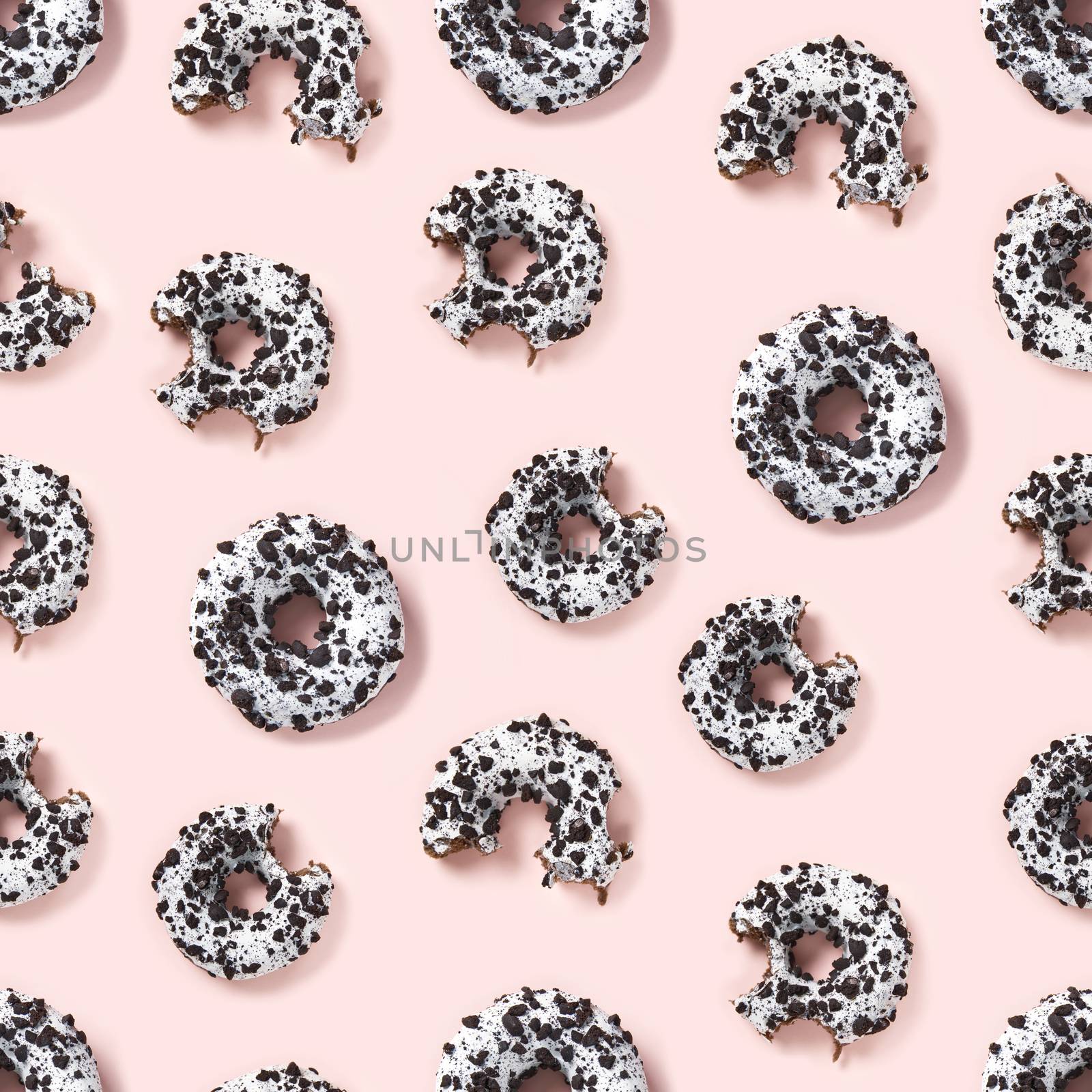 quality seamless pattern of donuts on a pink background top view. Flat lay of delicious nibbled chocolate donuts. by PhotoTime