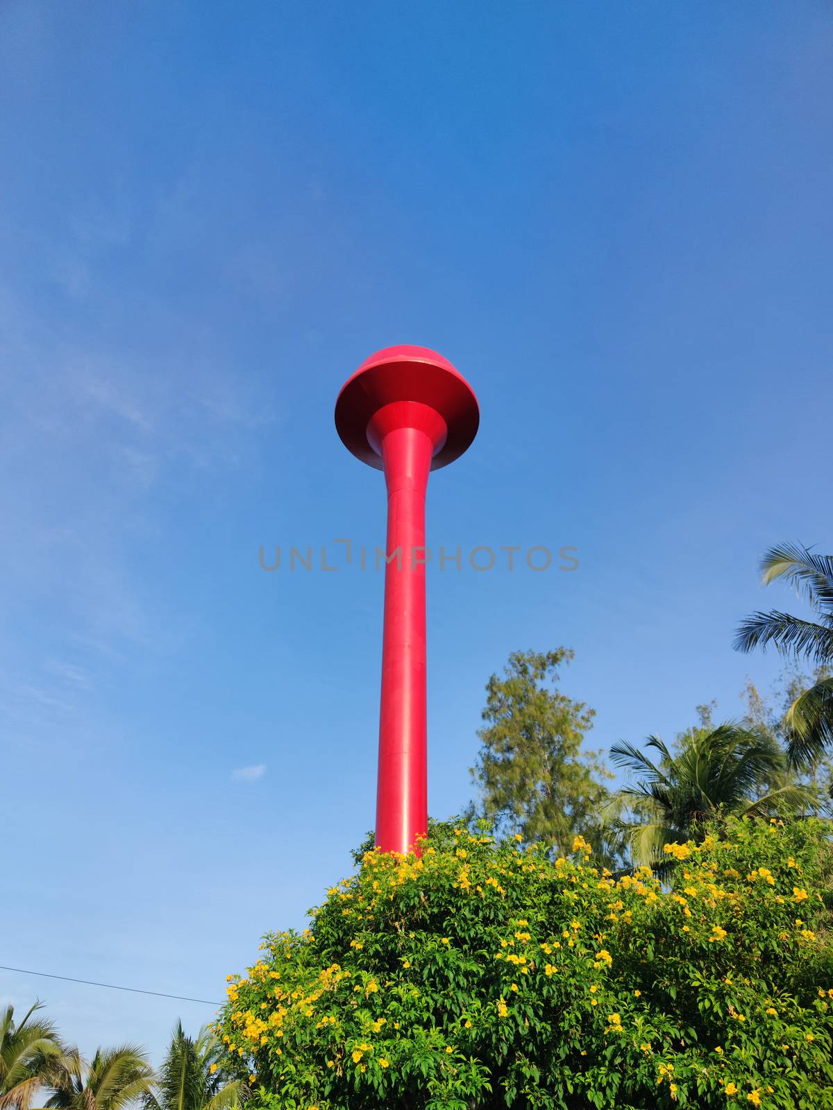 red thai water tower tank with blue sky. Vertical photo. by tidarattj