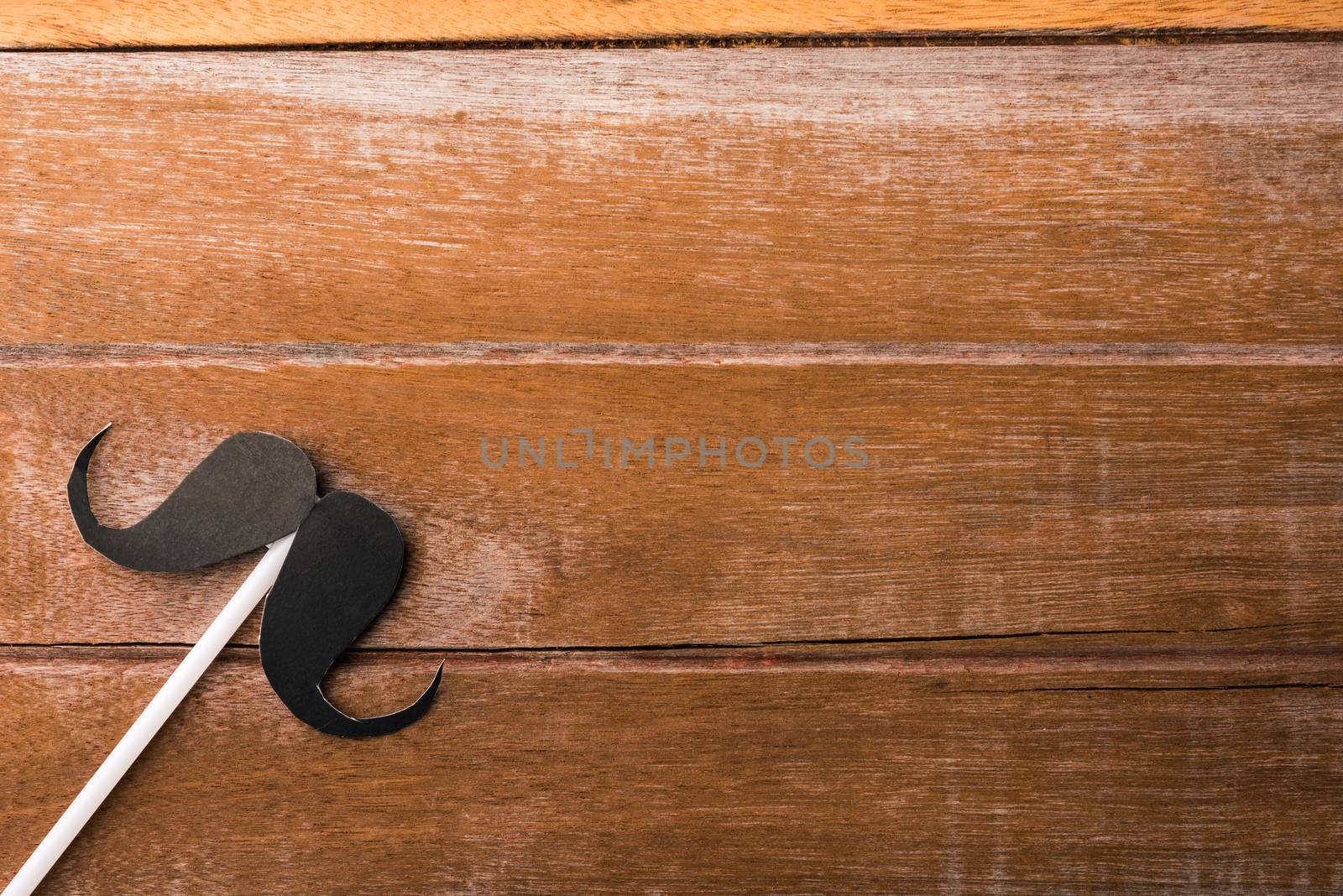 Black mustache paper on wooden background by Sorapop