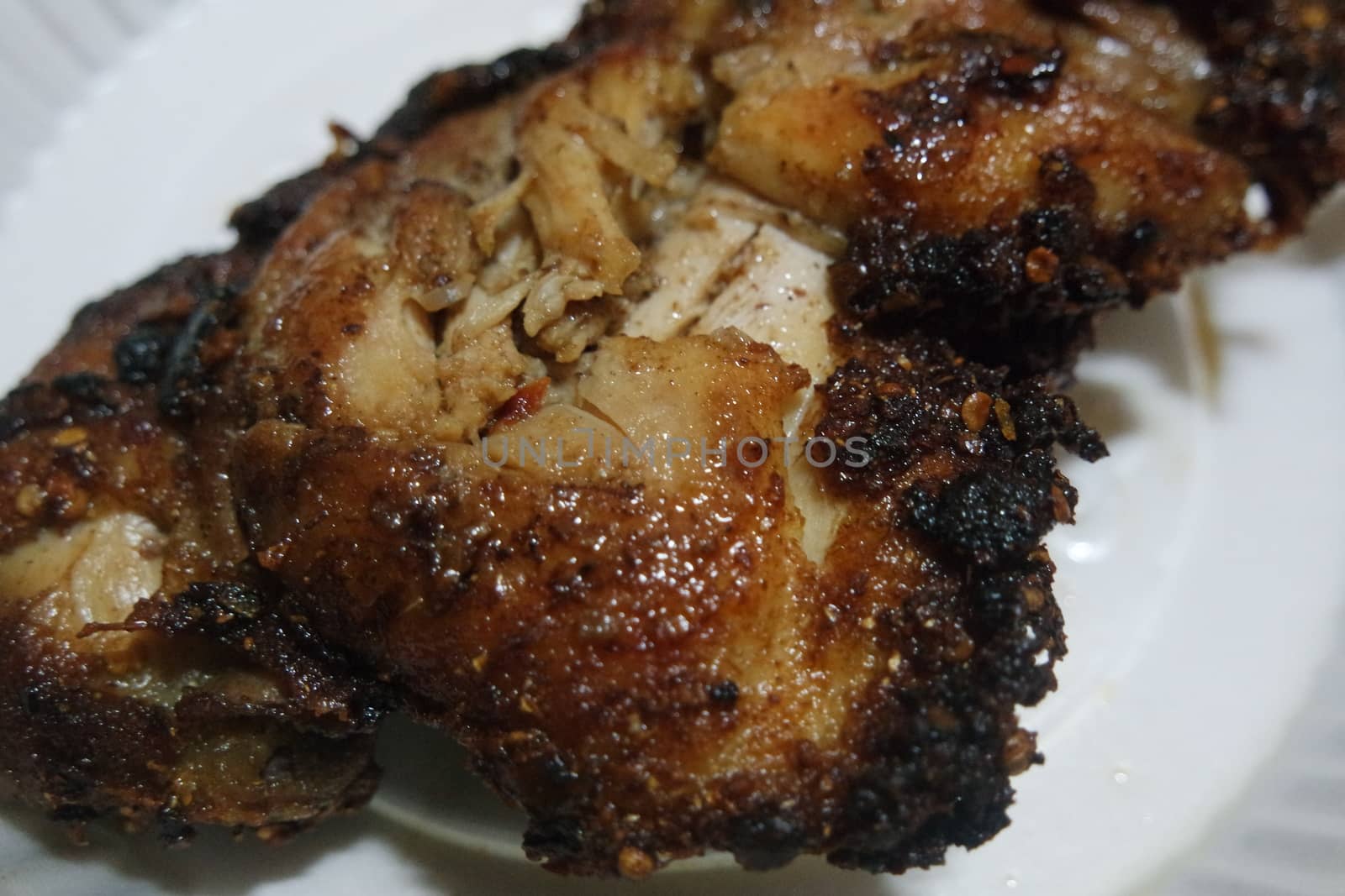 Close up of roasted chicken pieces in a white plate served for meal. Meat background for restaurant advertisements