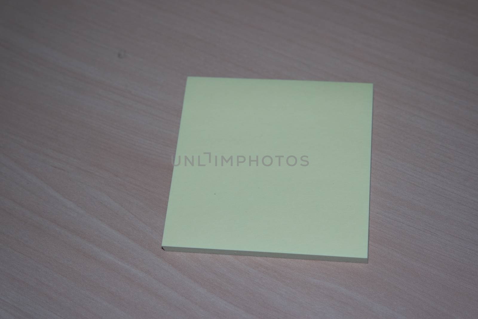 Yellow sticky note paper placed on a wooden table by Photochowk