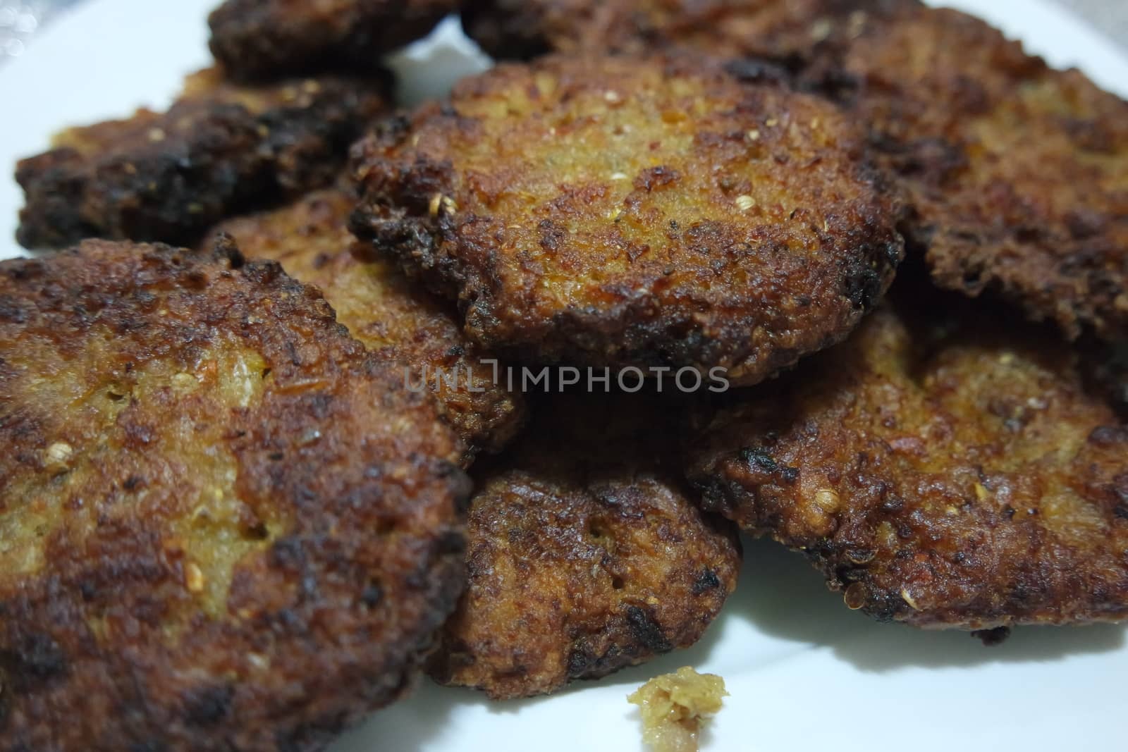 Delicious spicy fried round kebab served in a white ceramic plate on wooden floor