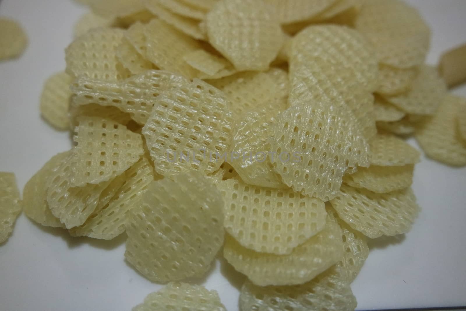 Closeup view with selective focus on dried chips as fast food for tea break. Potato chips with spices sprinkled on it. Fast food background for advertisements.