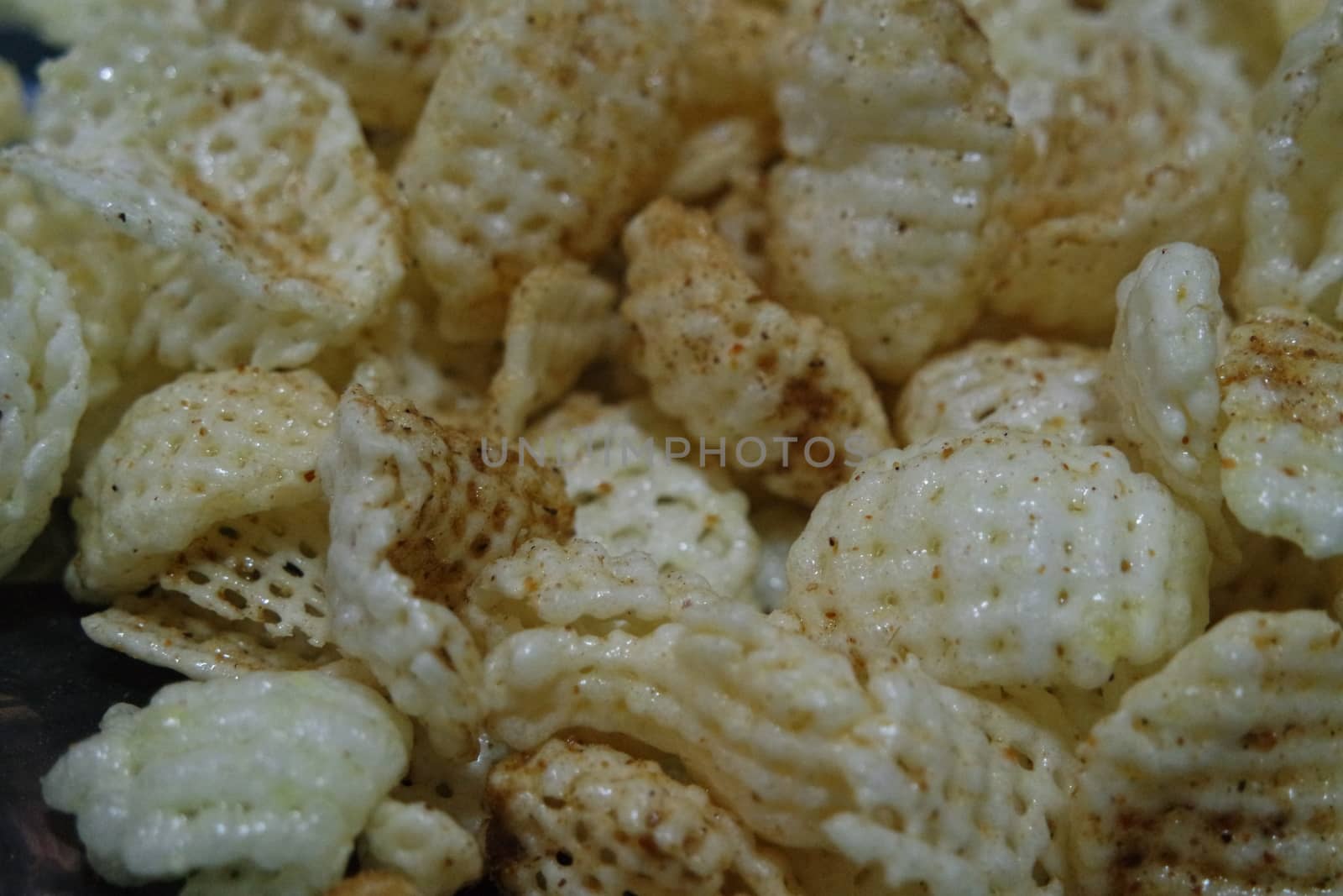 Closeup view of freshly fried chips as fast food for tea break. Potato chips with spices sprinkled on it. Fast food background for advertisements.