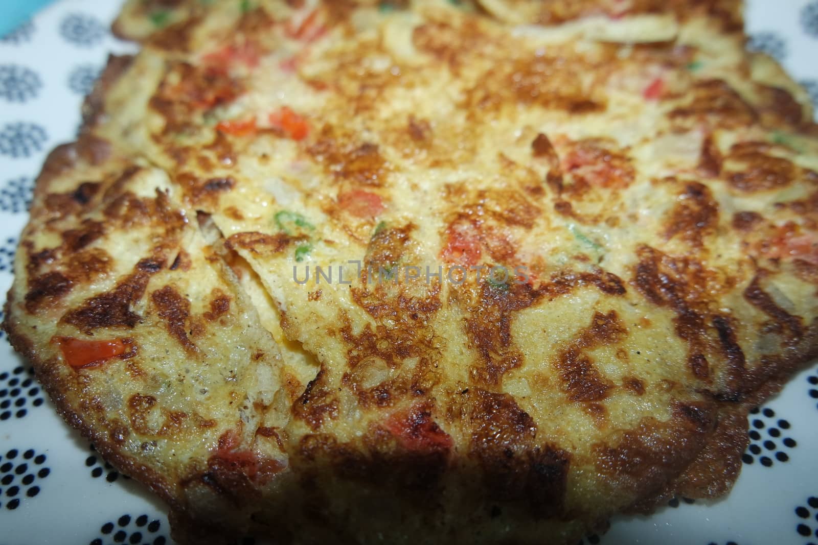Close-up view with selective focus of egg omelet with peppers and spices sprinkled