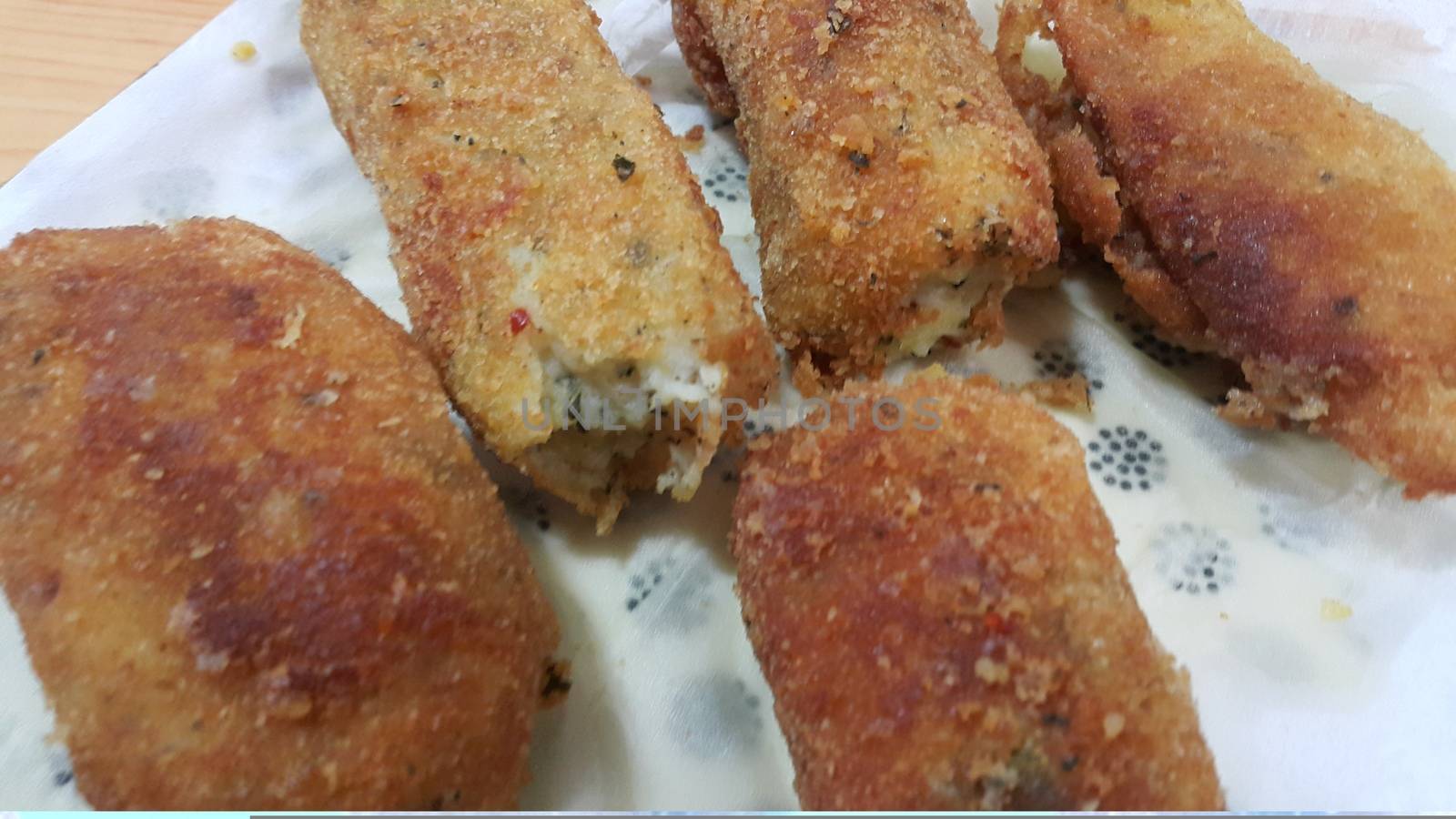 Closeup perspective view of home made spicy and delicious croquettes served in ceramic plate over wooden floor