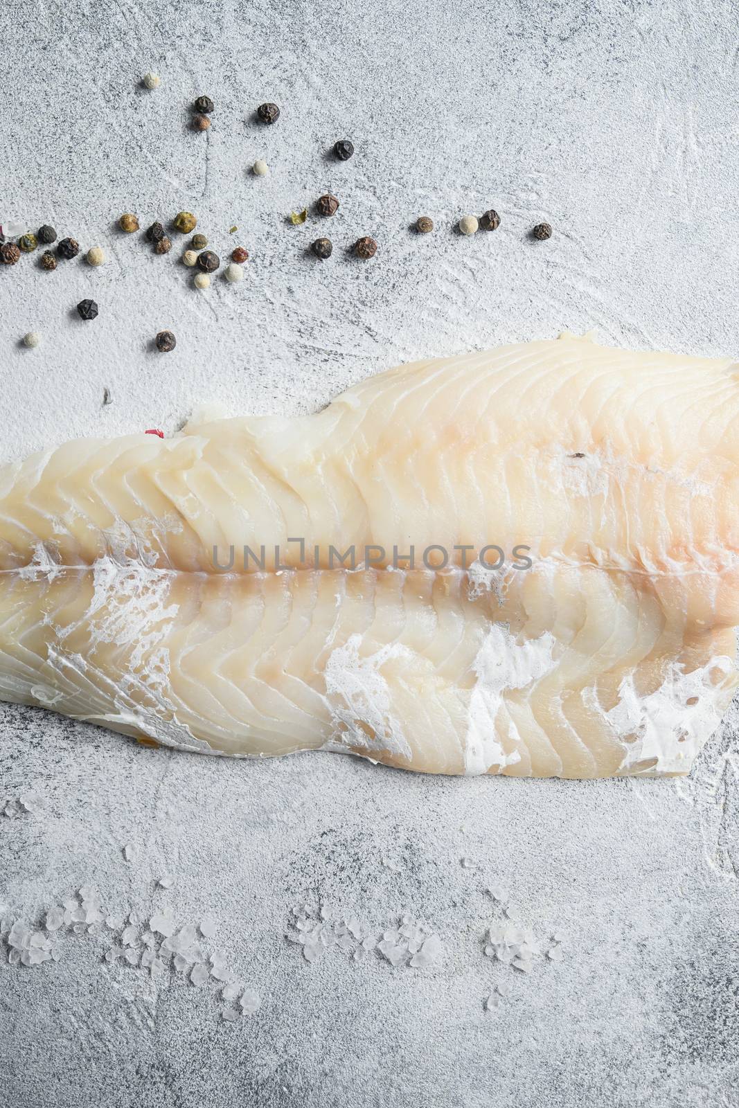 Cod fillets on a grey concrete background for the preparation of a healthy dish top view close up vertical.