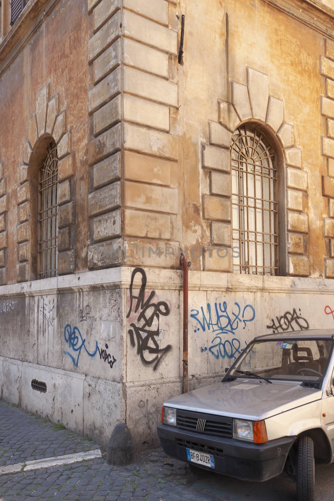 Rome, Italy - June 28, 2010: An old car from the 90's remains parked on a corner of an anonymous street in Rome.