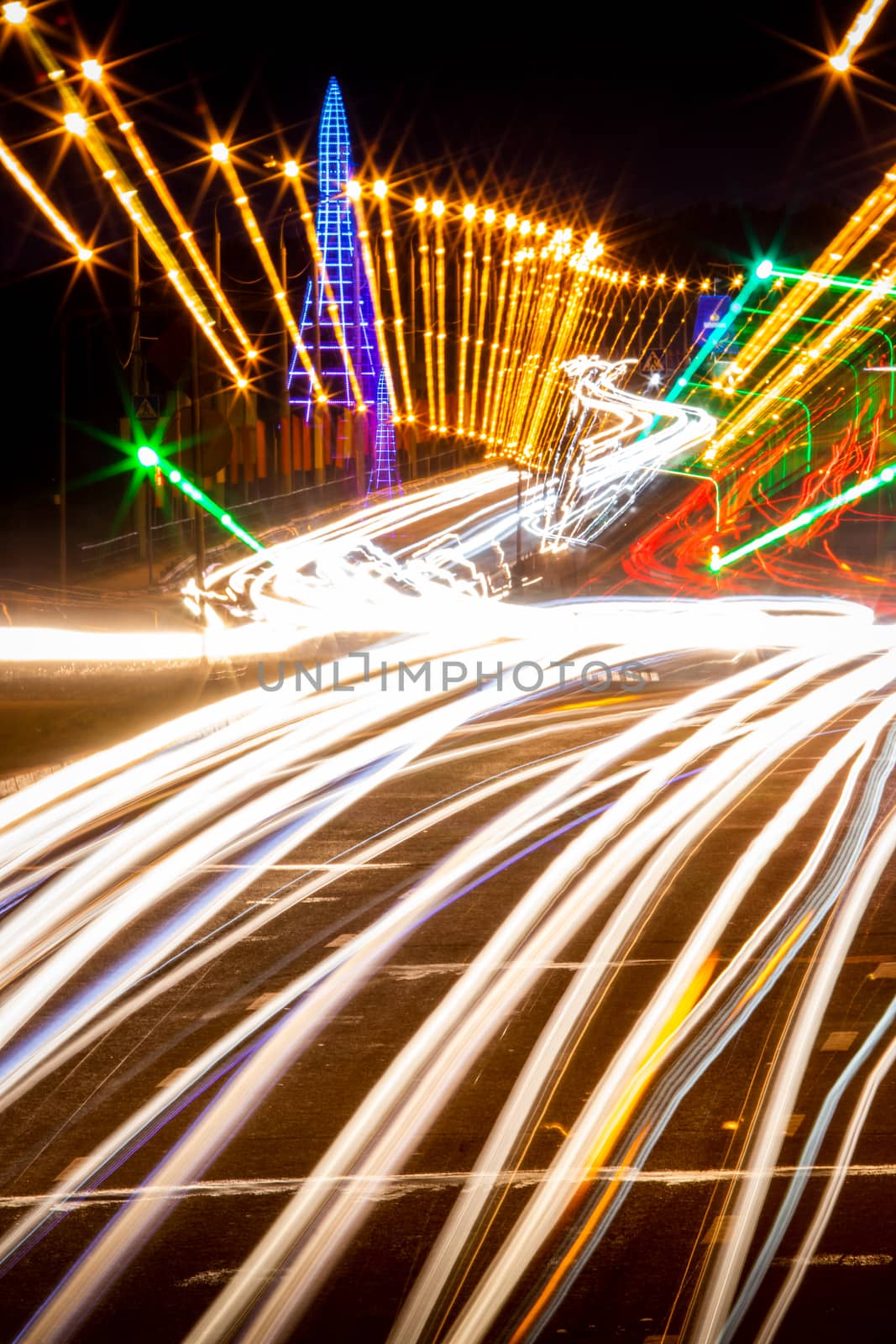 Traces of headlights from cars moving at night on the bridge, illuminated by lanterns. Abstract city landscape with highway at dusk. 