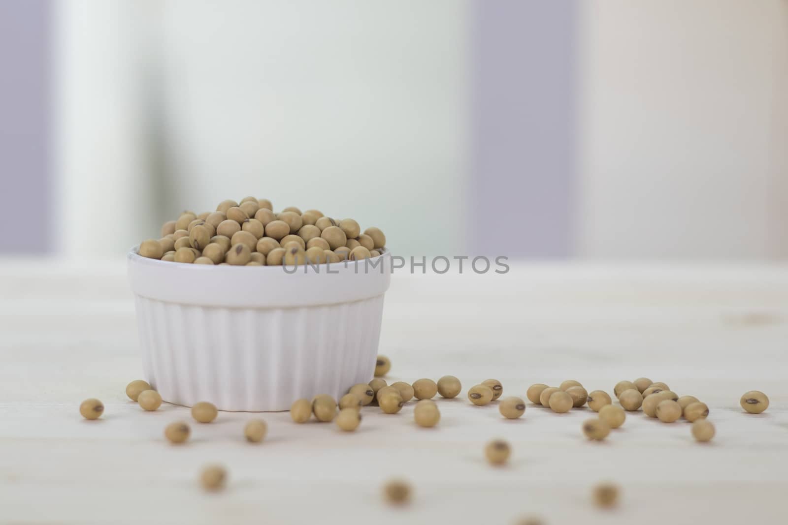 The soybeans are in the white cup placed on the wooden table.