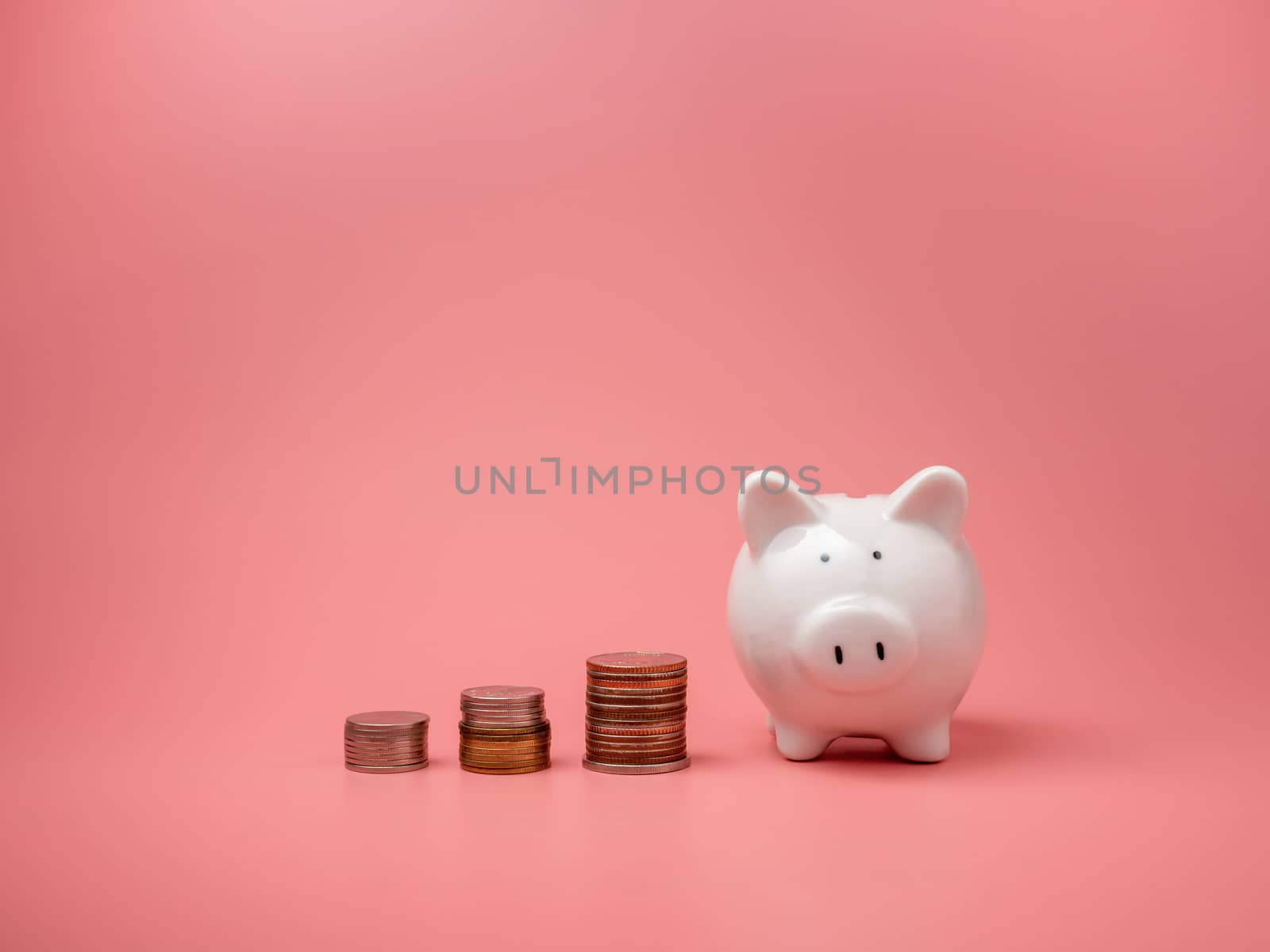 White piggy bank and coin On a pink background with copy space.