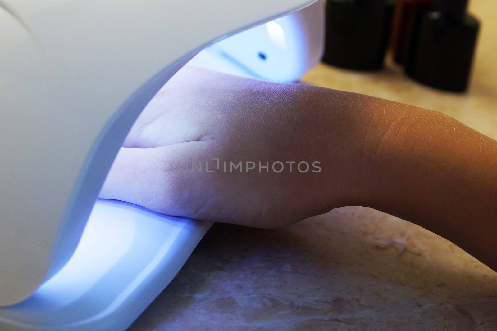 female hand in a UV lamp for nail manicure close up