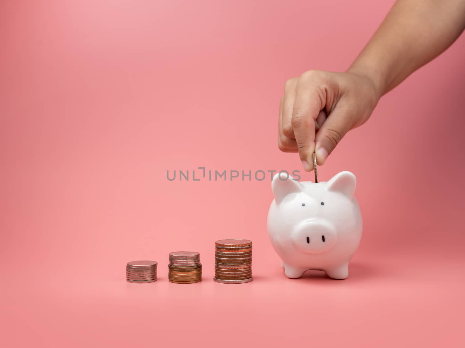 White piggy Bank and coin and human hand putting coin in piggy b by Unimages2527