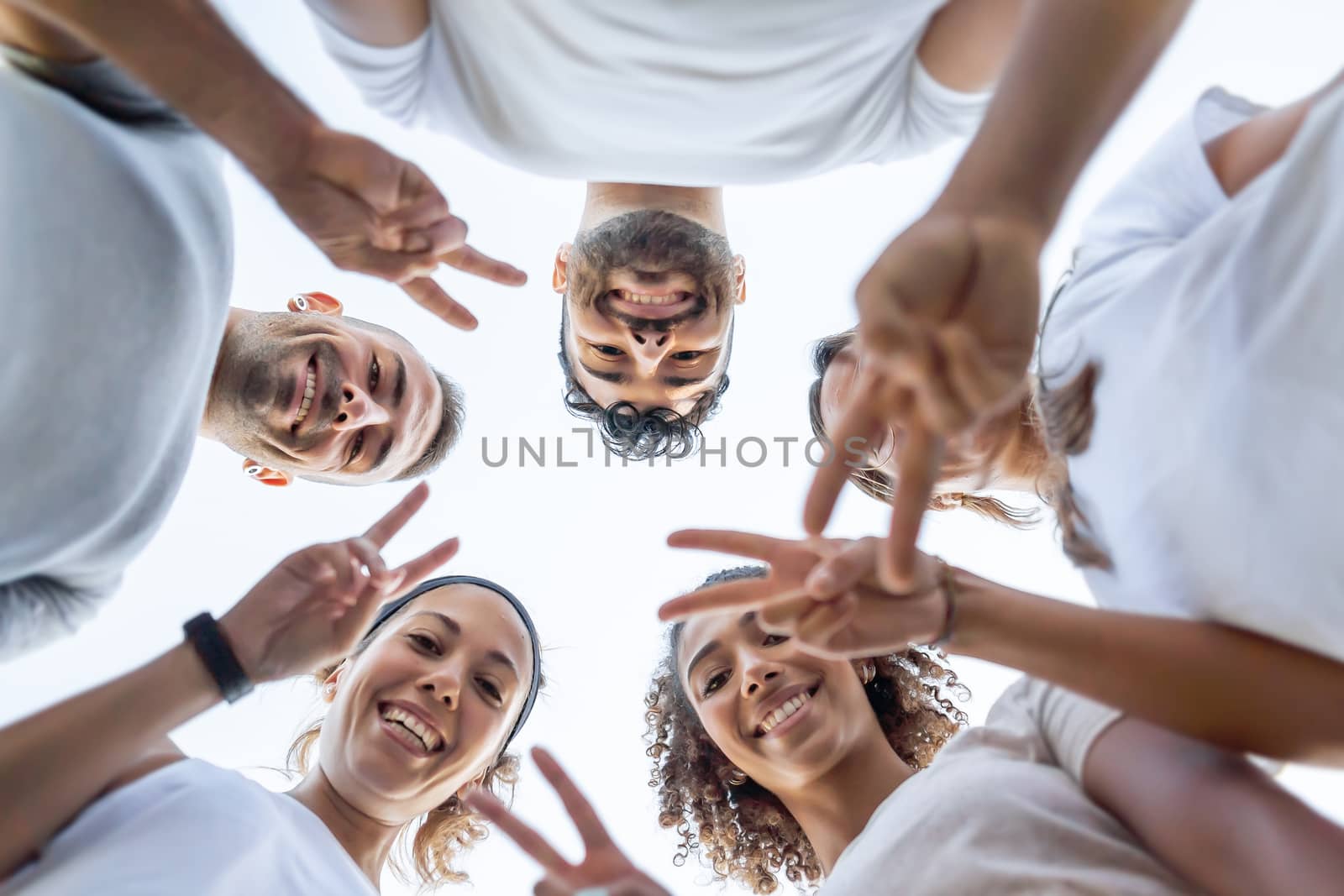 Group of young beautiful friends looking down at the camera showing fingers v-sign - Low angle view of five cute people doing victory sign together by robbyfontanesi