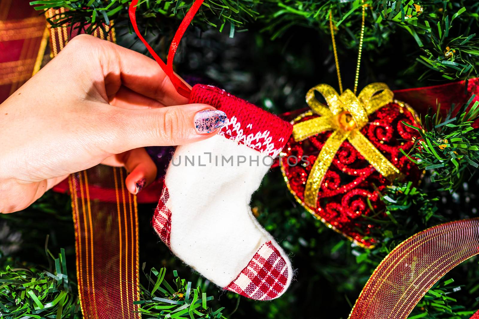 Decorating Christmas tree, hand putting Christmas decorations on by vladispas