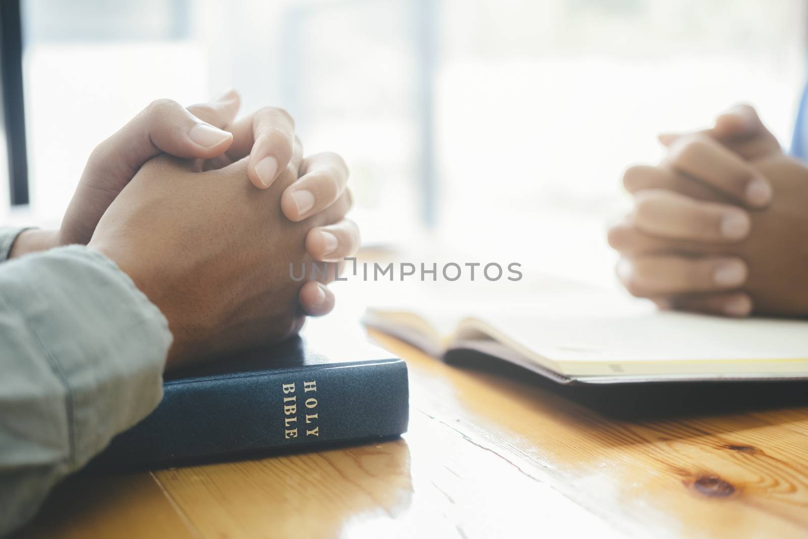 Two christian people are praying together over holy bible.