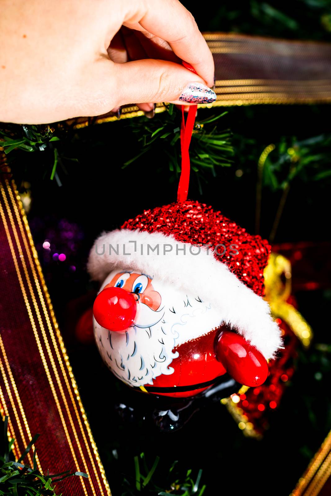 Decorating Christmas tree, hand putting Christmas decorations on fir branches. Christmas hanging decorations.