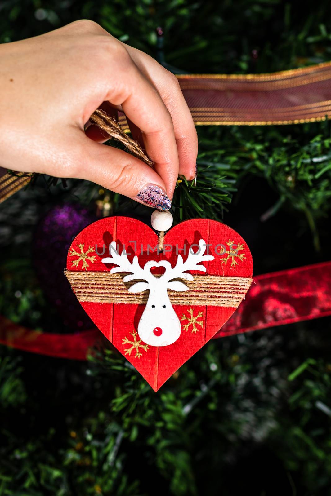 Decorating Christmas tree, hand putting Christmas decorations on fir branches. Christmas hanging decorations.