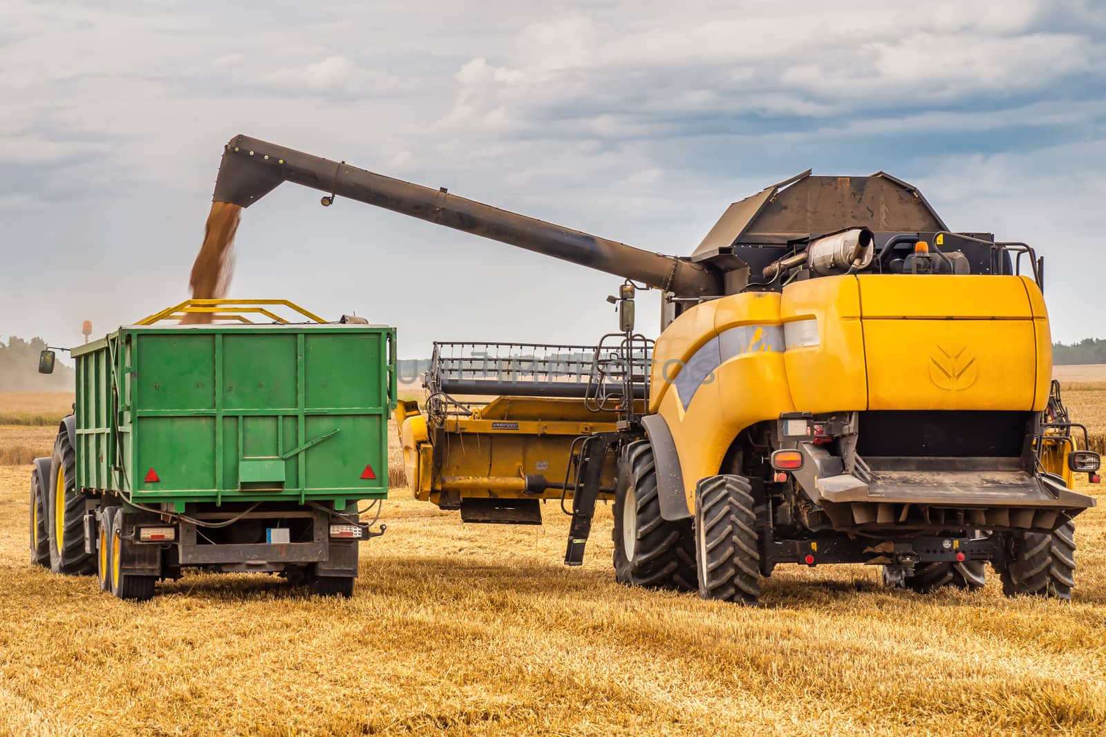 Harvester Combine and Tractor Working on The Large Wheat Field.