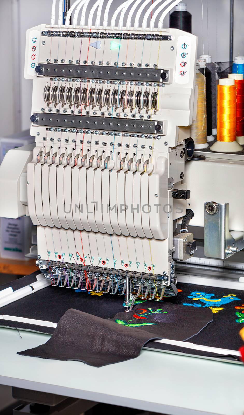 Industrial embroidery machine with multicolored threads, close-up, vertical image. by Sergii