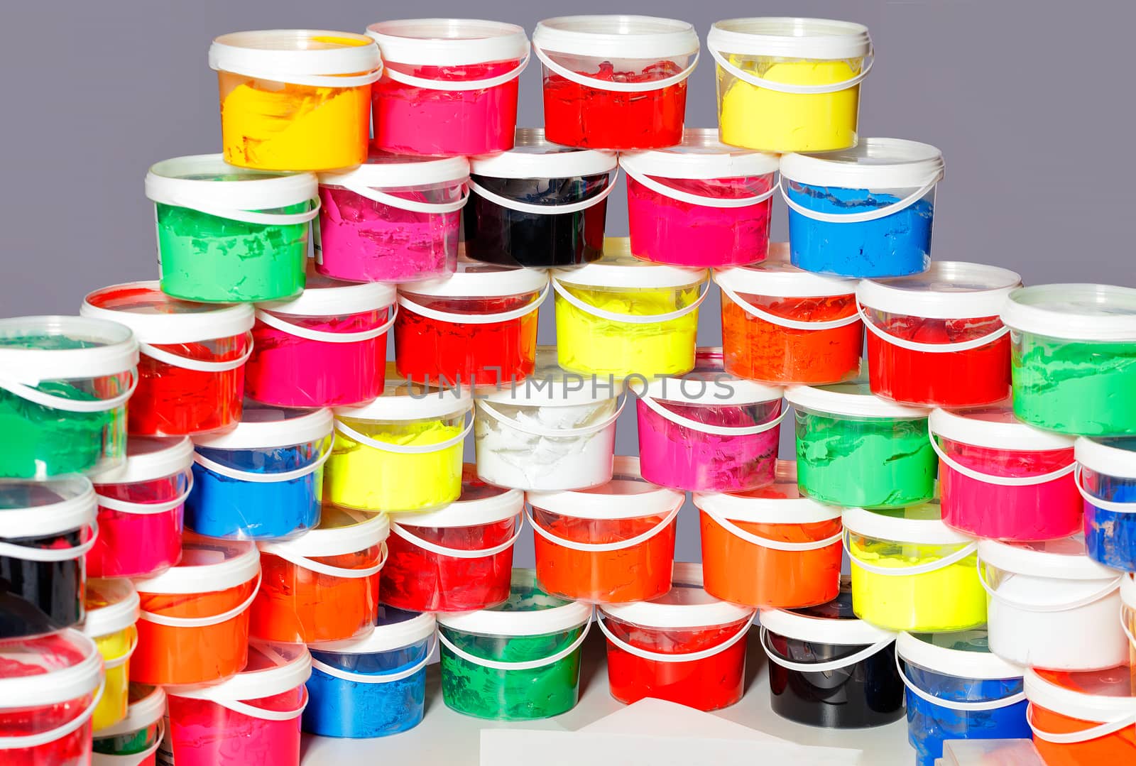 Screen-printing ink in a variety of vibrant colors is laid out in a semicircle and a slide in transparent plastic containers.