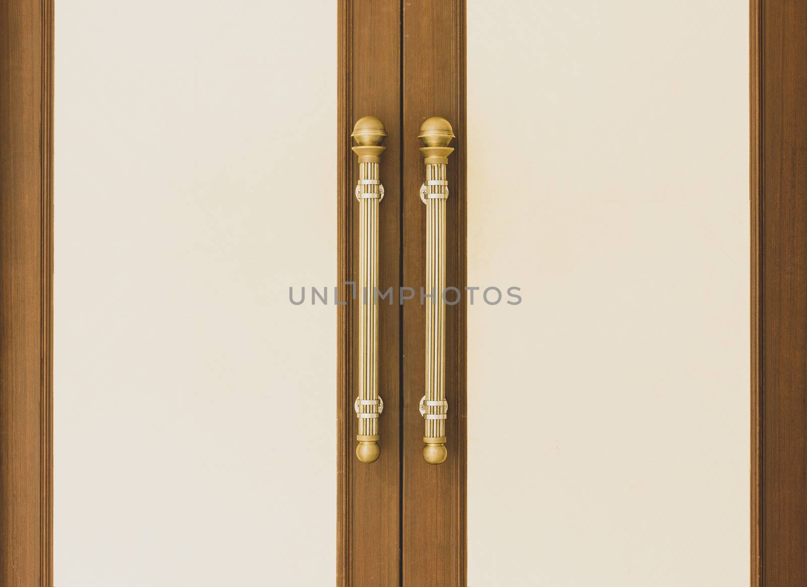 Vintage gold door handle front side of entrance interior home. Close-up closed light wooden doors in style in the interior. Doorways fittings for hotel indoor design. House apartment entryway