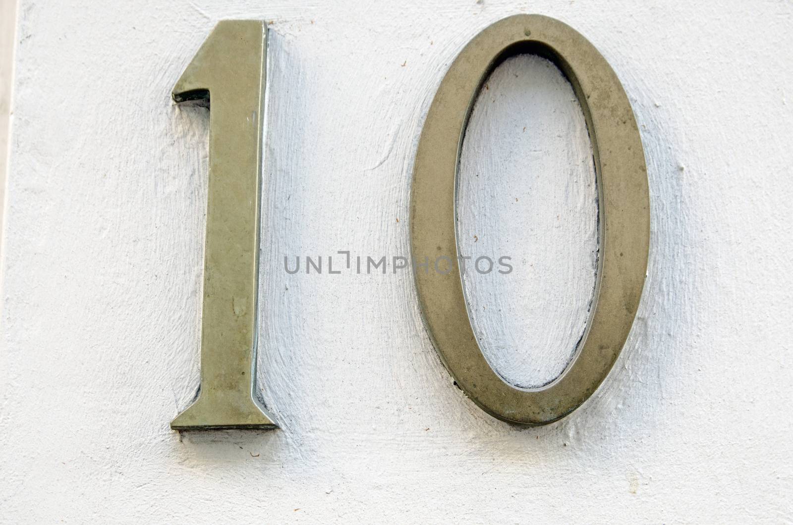 Brass number 10 on wall by BasPhoto