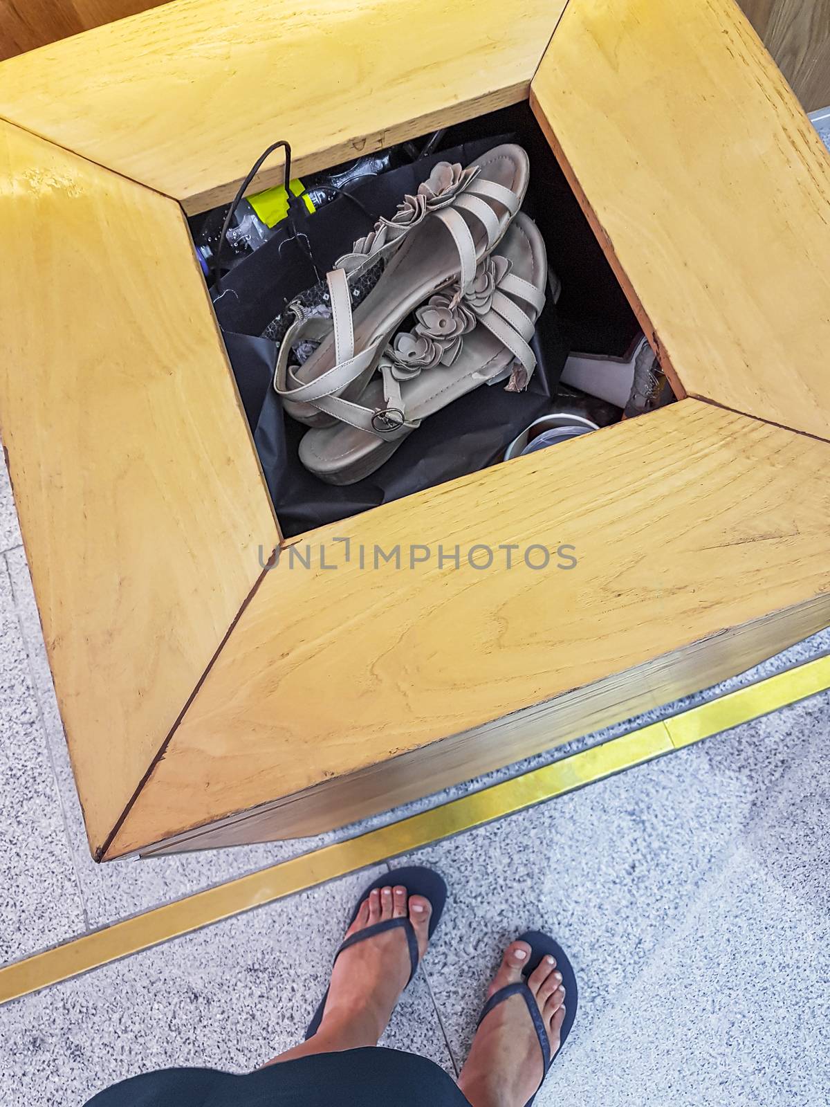 Woman throws her flip-flops sandals into a garbage can. by Arkadij