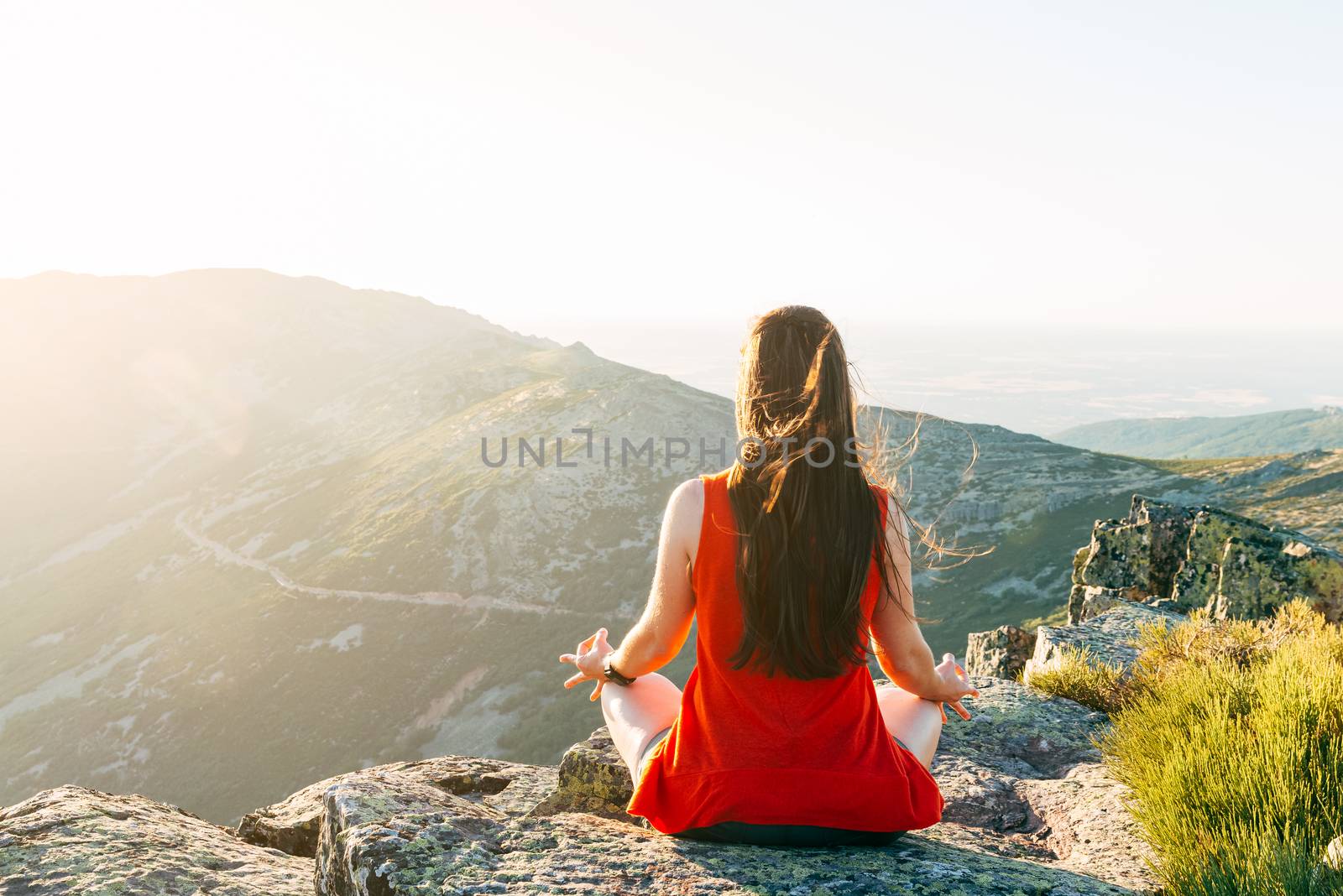Woman practices yoga and meditates on the mountain by Fotoeventis