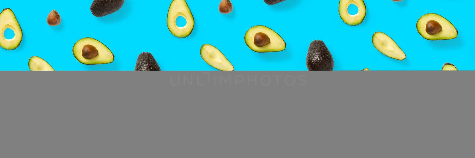 Avocado banner. Background made from isolated Avocado pieces on blue background. Flat lay of fresh ripe avocados and avacado pieces. by PhotoTime