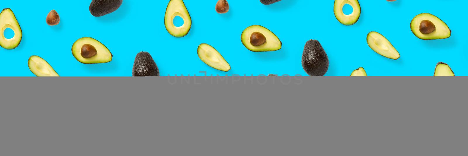 Avocado banner. Background made from isolated Avocado pieces on blue background. Flat lay of fresh ripe avocados and avacado pieces. by PhotoTime