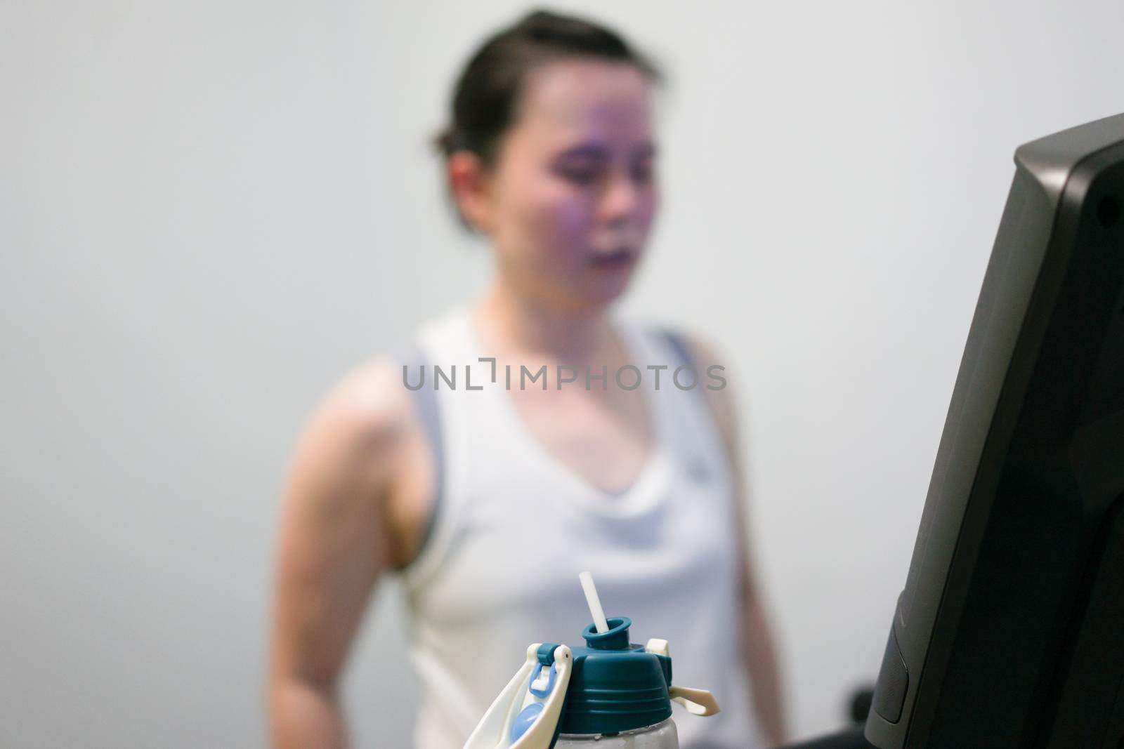 water bottle on blur background of tired woman jogger on treadmill