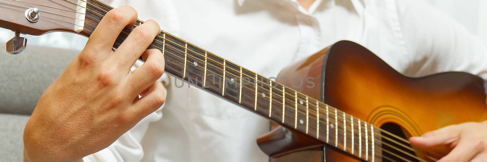 Young boy playing guitar. Close-up of man hand playing classic guitar. teenager learning playing guitar. Banner or panoramic shot. by PhotoTime