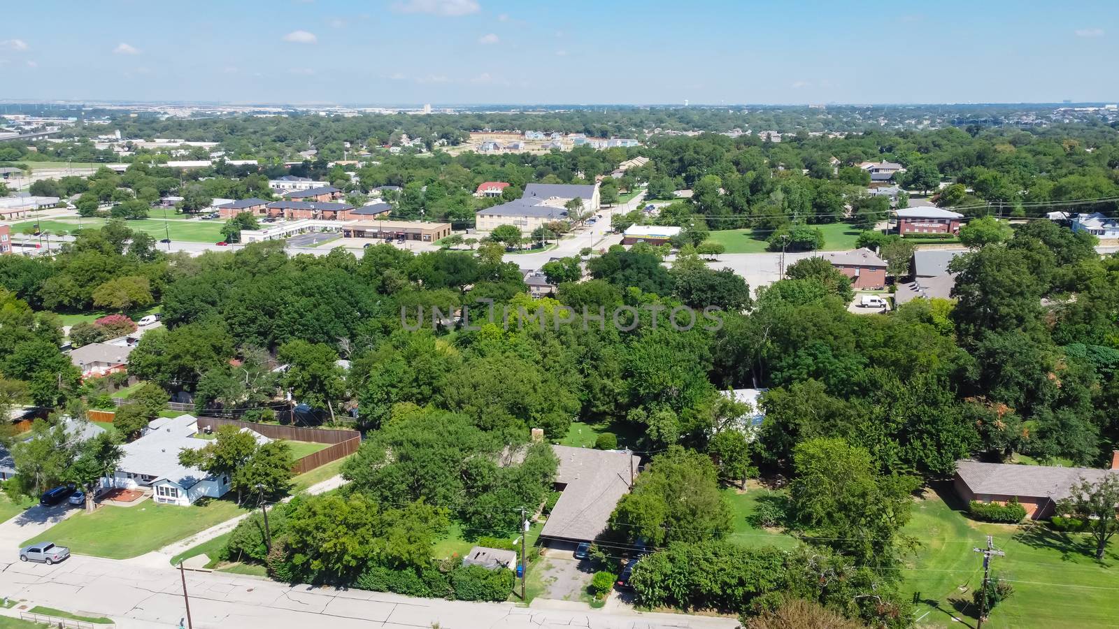 Top view green residential area near historic downtown Carrollton, Texas with single family houses surrounded by mature trees.