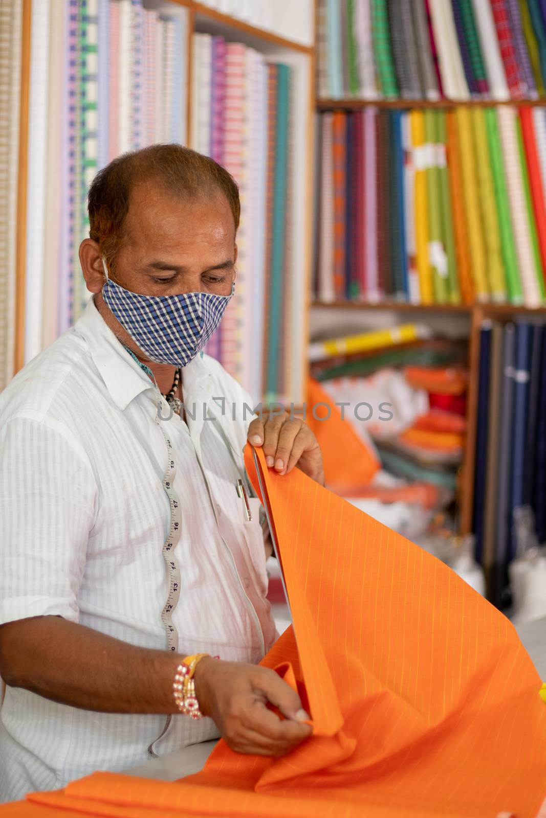 Shopkeeper in medical mask measuring cloth using scale or ruler - concept of back to business, business reopen after covid-19 or coronavirus pandemic