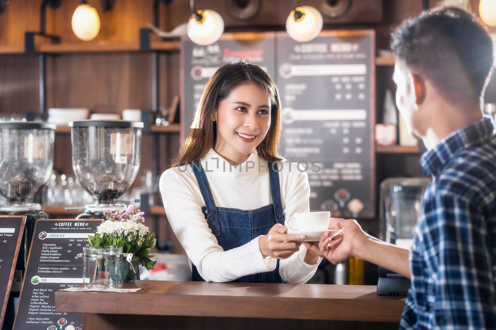 Asian Barista of Small business owner serving a cup of coffee to young customer at the coffee counter in coffee shop, Small business owner and startup in coffee shop and restaurant concept