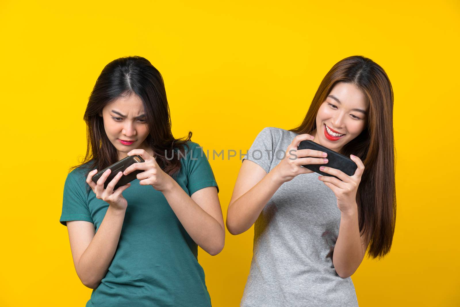 Two Happiness Asian smiling young woman gamer using smart mobile by Tzido