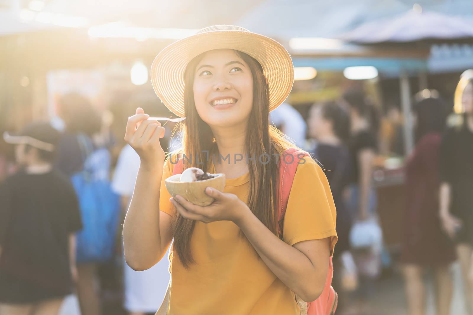 Asian traveling woman eating ice scream in chatujak market at the sunset time at Bangkok, Thailand, Travel and Tourist, walking street and food market, shopping and lifestyle concept