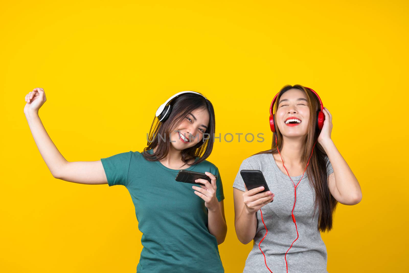 Two Happiness Asian smiling young woman wearing wireless headpho by Tzido