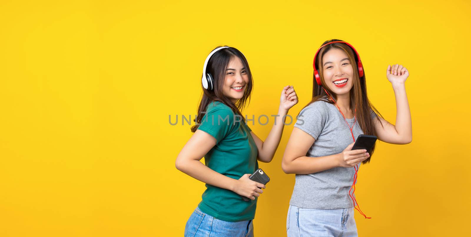 Two Happiness Asian smiling young woman wearing wireless headpho by Tzido