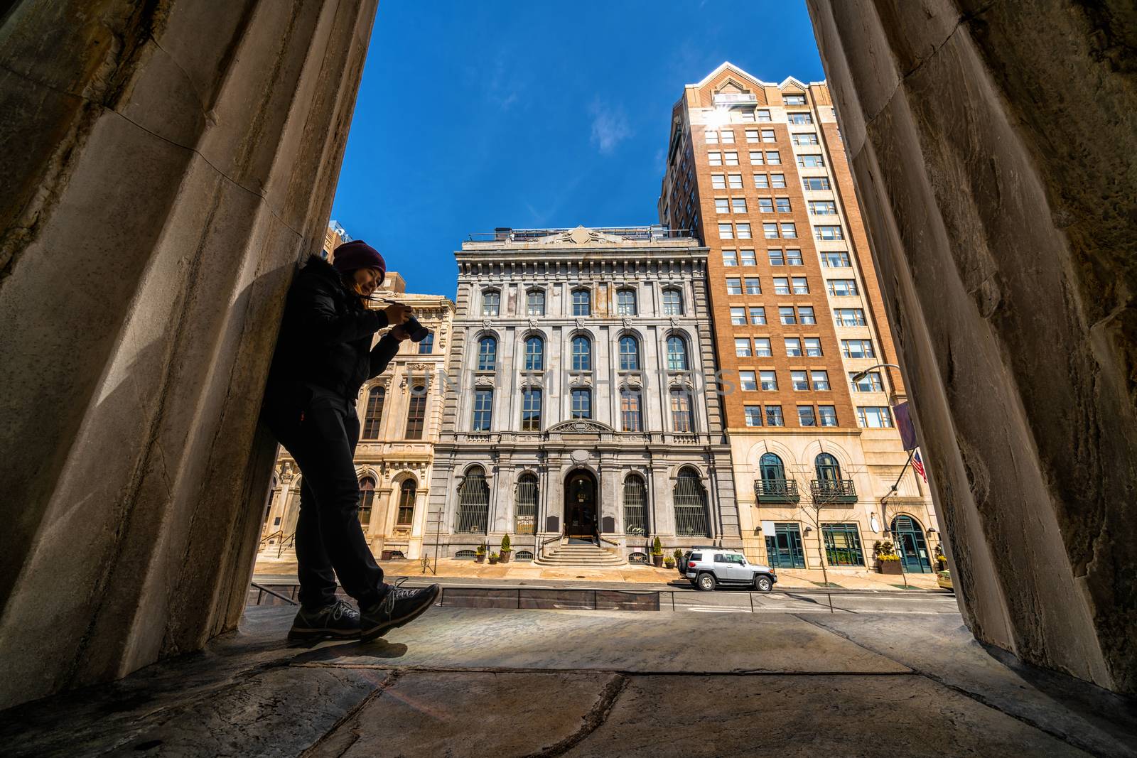 Asian young woman checking and using the camera over the bank of philadelphia, United states if America, Architecture and building with tourist concept